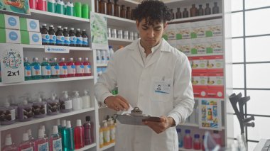 Hispanik eczacı, iyi aydınlatılmış bir mağazadaki ilaç ve sağlık ürünleriyle dolu rafların arasında panoyu inceledi.