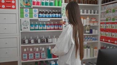 Modern bir eczane içinde raflar düzenleyen Asyalı bir eczacı.