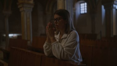 Genç bir İspanyol kadın, tarihi bir İtalyan kilisesinde kutsal bir şekilde dua ediyor. İnancını dingin bir ibadet anında sergiliyor..