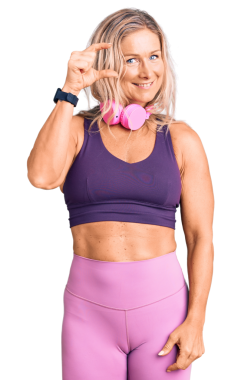 Orta yaşlı sarışın kadın portresi spor kıyafetleri içinde gülümseyen ve şeffaf arka planda boy gösteren. 