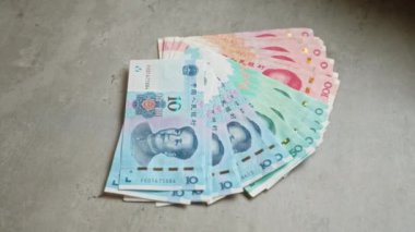 Çin Yuan banknotları farklı değerler ve canlı renkler içeren beton bir yüzeye yayıldı.