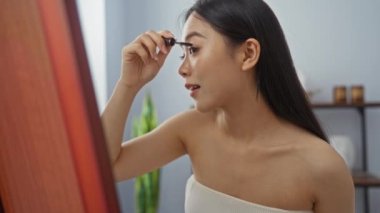 Sakin bir kaplıca odasında aynanın önünde makyaj yapan bir kadın sakin ve rahatlatıcı bir güzellik ortamı yaratıyor.