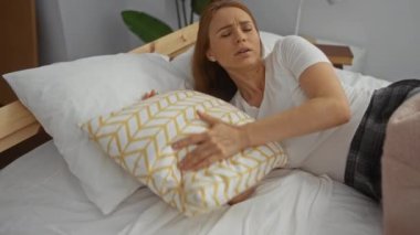 Beyaz yastıkları, ahşap çerçevesi ve yumuşak ışıklandırması olan rahat ve rahat bir yatak odasında dinlenen bir kadın..
