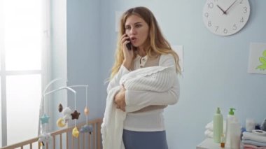 Parlak bir çocuk odasında telefonla konuşurken kucağında beşikte ve saatte endişelerini belli eden bir kadın rahatlatıcı ama gergin bir ev sahnesi yaratıyor..