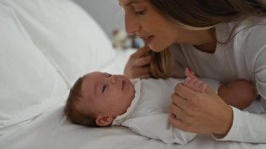 Anne, küçük kızıyla huzurlu bir yatak odası ortamında rahat bir yatakta sevgi dolu bir şekilde iletişim kuruyor. Aile birlikteliğini ve sıcaklığını vurguluyor..