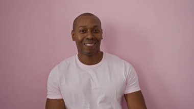 Genç, gülümseyen bir adam pembe bir arka plana başparmak basar, pozitif bir hava yayar ve kendine güveni tecrit edilir, neşeli ifadesine odaklanmasına olanak sağlar..