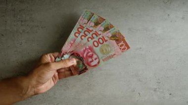 Yeni Zelanda Doları banknotları tutan adam kapalı bir alanda beton bir arka plan karşı.