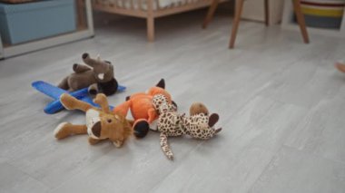Doldurulmuş oyuncakları yatak odasına yerleştiren, onları sepete koyan, onları besleyen ev ortamını gösteren bir kadın..