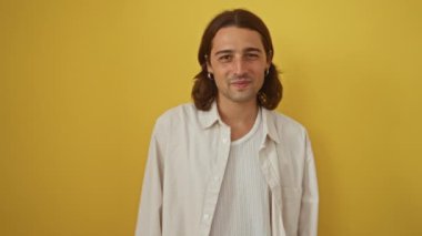 İzole edilmiş sarı arka planda gülümseyen genç İspanyol adam yakışıklı görünüyor.