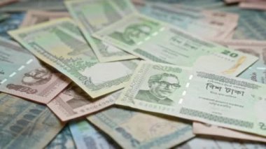 Bangladeş banknotları çeşitli mezhepleri gösteren ve önde gelen figürlerin yer aldığı bir yüzeye saçılmış, Bangladeş 'in para birimini vurguluyor..