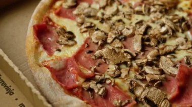 Mantarlı, jambonlu ve eritilmiş peynirli sıcak pizzanın nefis yakın çekimi, hızlı ve lezzetli bir yemek için mükemmel..