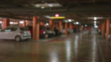Bulanık araba manzaralı yeraltı otoparkı ve loş ışıklı arka planda sönmüş ışıklar.