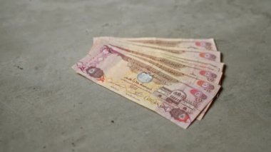 Birleşik Arap Emirliklerinin banknotları gri beton bir yüzeye saçılmıştır.