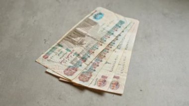 Mısır banknotları gri beton bir yüzeye saçılmış ve finansal temayı ayrıntılı para birimi özellikleriyle vurguluyor.