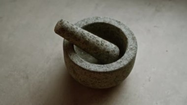 Beton yüzeydeki taş havan topu geleneksel mutfak ortamlarında baharat ve bitkileri öğütmek için kullanılan rustik mutfak aletini gösteriyor.