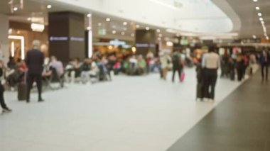 Bavullu bulanık gezginler yoğun havaalanı terminalinde hareketli işaretler ve dağınık ışıklandırma ayarlarında hareketli iç atmosfer ile gezinirler..