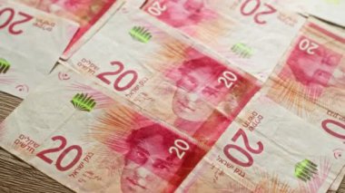 İsrail şekel banknotları ahşap bir masaya yayılmış, 20 ve 50 şekel banknotlar ayrıntılı tasarım ayrıntıları içeriyor..