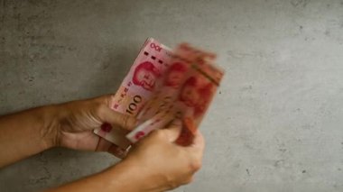 Çin para birimini ve finansal konsepti gösteren somut bir geçmişi olan Yuan paralarını sayan bir adam.