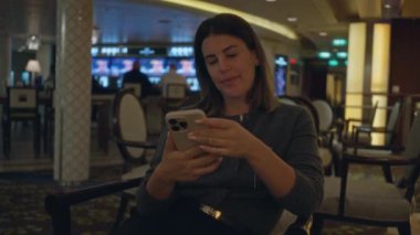 Lüks bir kapalı bar ortamında, şık dekorlu ve ortam aydınlatmalı telefonda konuşan bir kadın rahat bir sohbet atmosferi yakalıyor..