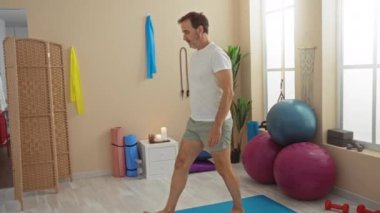 Dingin bir sağlık odasında egzersiz topları ve rahatlatıcı bir atmosferle yoga yapan olgun bir adam..