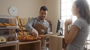 Pastanede kadınlara kruvasan servis eden bir adam. İçi ekmek dolu.