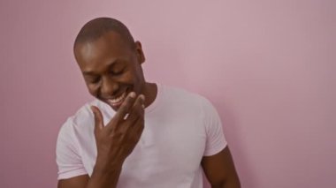 Pembe arka plana gülümseyen, beyaz gömlek giyen, mutluluk ve sadelik taşıyan bir adam..