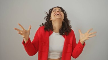 Genç, güzel, esmer saçlı, kırmızı kazak giyen, izole edilmiş beyaz bir arka planda neşeyle gülen İspanyol bir kadın..