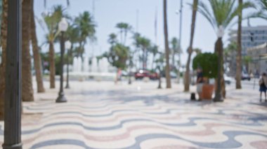 Bulanık palmiye ağaçları, insanlar ve güneşli bir gökyüzü altında İspanya 'da dalgalı mavi şablon asfalt ile silikon gezinti görüntüsü.