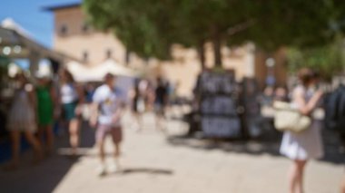 Bulanık kalabalık Mallorca 'da güneşli bir günün tadını çıkarıyordu. Arka planda erkek ve kadınların yürüdüğü bir pazar yeri vardı.