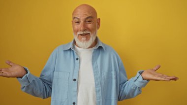 Sarışın, sakallı ve kel saçlı, neşeli bir ifadeyle izole edilmiş sarı bir arkaplanda, mavi tişörtlü ve beyaz tişörtlü yakışıklı bir adam.