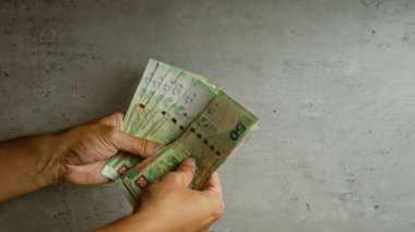 El ele tutuşan Hong Kong doları banknotları somut bir arkaplan karşısında mali işlemler ve döviz kurları konseptini gösteriyor