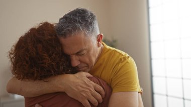 Erkek ve kadın sevgi dolu bir şekilde evde oturma odasında oturuyorlar, sevgi ve duygusal destek gösteriyorlar..