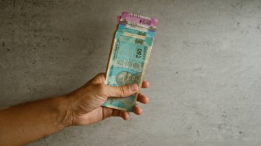 Elinde Hindistan banknotları tutan adam beton bir arka planda