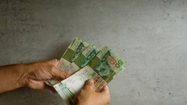 Hong Kong dolarlarını beton bir duvara dayayan ve yerel bir dokunuşla para ve finansal konsepti ön plana çıkaran bir adam..