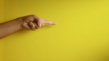 Parmakla işaret eden erkek eli parlak sarı arka planda yön ve vurgu ifade ediyor.