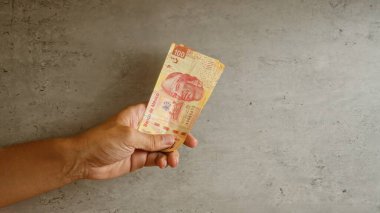 Beton bir arka planda Meksika Pezosu ile el ele tutuşmak.