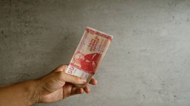 Somut bir zemine karşı el ele tutuşan İzlanda Krona banknotu, para biriminin eşsiz tasarım özelliklerini ve dokusunu vurguluyor.