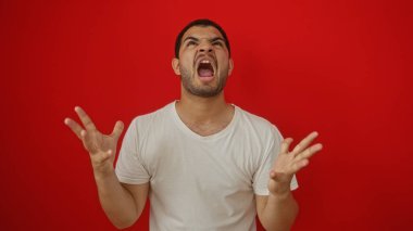 Öfkeli bir şekilde kırmızı arka planda izole edilmiş genç İspanyol adam.
