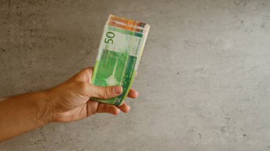 Norveç 'teki para biriminin canlı tasarımı ve finansal bağlamının altını çizerek, gri beton bir zemine karşı bir yığın Norveçli kron banknotları tutarak.