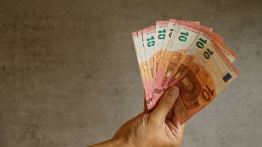Avrupa 'daki zenginlik, finans ve para birimlerini temsil eden somut bir geçmişe karşı elinde çoklu avro banknotları, ayrıntılı parmaklar ve para üzerinde güçlü bir kavrama ile.