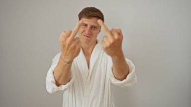 İzole edilmiş beyaz bir arka plan üzerine cüppeli genç adam, her iki orta parmağını da küstah bir ifadeyle kaldırıyor, tavır ve başkaldırı unsurlarını yakalıyor.