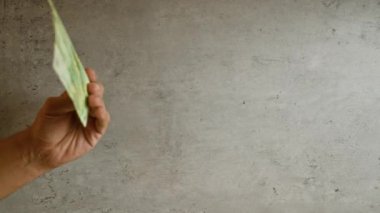 Elinde dört Romen leyi banknotları tutan adam, somut bir arkaplanda el, para ve dokuyu vurguluyor..