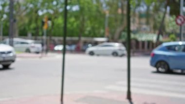 Arka planda ağaçlar ve arabalar olan bulanık bir açık hava sahnesi güneşli bir günde yoğun bir kavşakta çekildi.