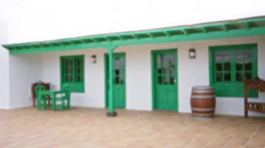 Lanzarote 'deki bulanık koloni tarzı yeşil ve beyaz bina. Kapıları, pencereleri, masaları ve fıçıları geleneksel estetiği gösteriyor.