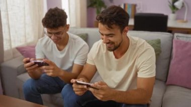 Baba ve oğul rahat bir oturma odasında video oyunları oynuyorlar. Güçlü bağlarını, kahkahalarını ve keyiflerini rahat bir evde sergiliyorlar..