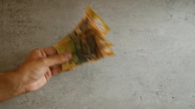 Elele tutuşan Avustralyalı 50 dolarlık banknotlar beton arka plan üzerinde bulanık hareket etkisine sahip.