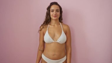 Genç İspanyol kadın bikinili, garip bir balık suratı yapıyor. Tuhaf, komik dudakları olan, soyutlanmış pembe arka planda.