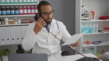 Tıbbi malzeme ve ekipmanların bulunduğu klinikteki belgeleri incelerken doktor telefonda konuşuyor.