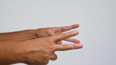 Adamın el hareketi iki numarayı gösteriyor. Parmakları düz beyaz arka plana doğru uzanıyor.