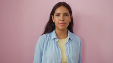 Genç bir kadın kendini gösterip gülümsüyor ve pembe arka planda 